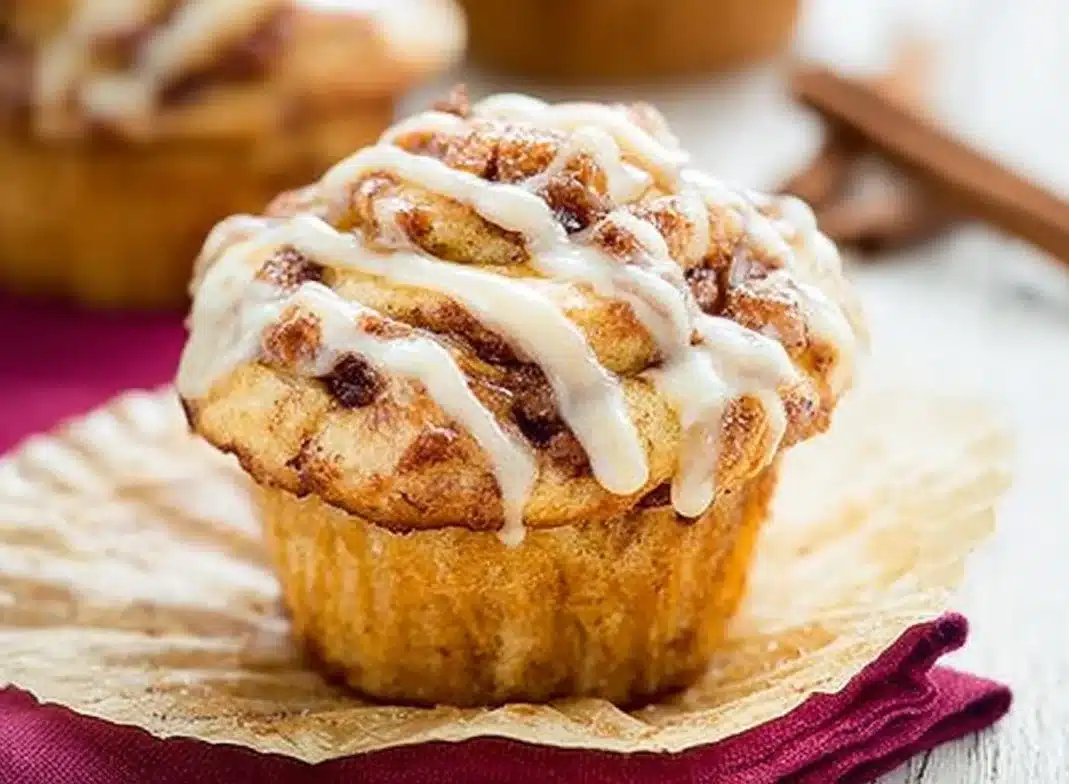 Freshly baked cinnamon roll muffins topped with icing and cinnamon sugar