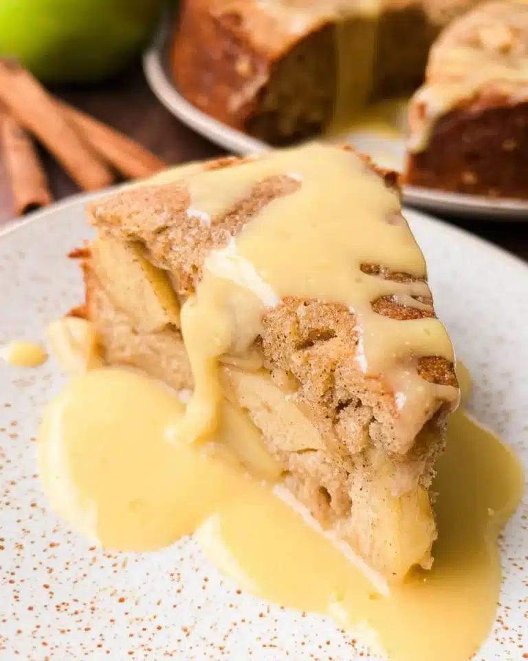 Slice of Irish Apple Cake served with creamy custard sauce on a rustic table