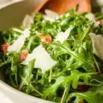 A vibrant arugula salad with cherry tomatoes and feta cheese serving on a plate