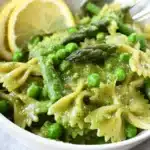 A bowl of vibrant Asparagus Pesto Pasta garnished with fresh herbs.