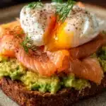 Avocado toast topped with a perfectly poached egg on whole grain bread