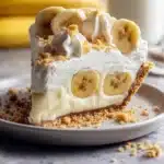 A delicious slice of Banana Pudding Pie topped with whipped cream and banana slices
