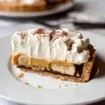 Delicious Banoffee Pie topped with banana slices and whipped cream.