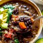 Bowl of delicious black bean soup garnished with herbs and spices.