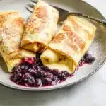 Delicious cheese blintzes served with fruit topping and powdered sugar