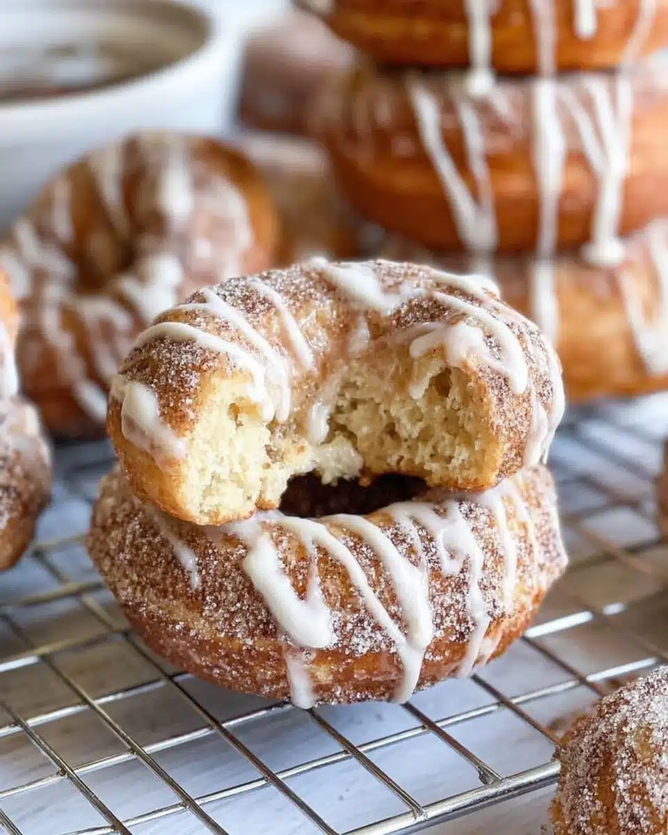 Freshly baked cinnamon roll donuts topped with icing and cinnamon sugar.
