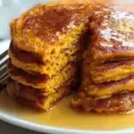 Fluffy sweet potato pancakes drizzled with syrup and topped with fresh berries.