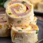 Ham and cheese roll ups served on a plate with fresh herbs