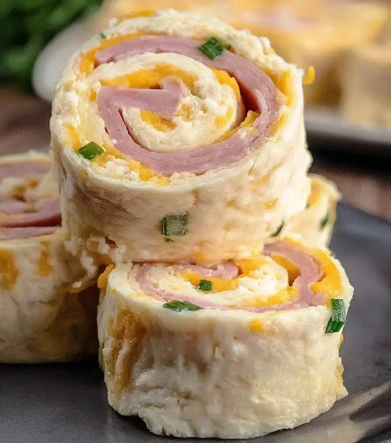 Ham and cheese roll ups served on a plate with fresh herbs