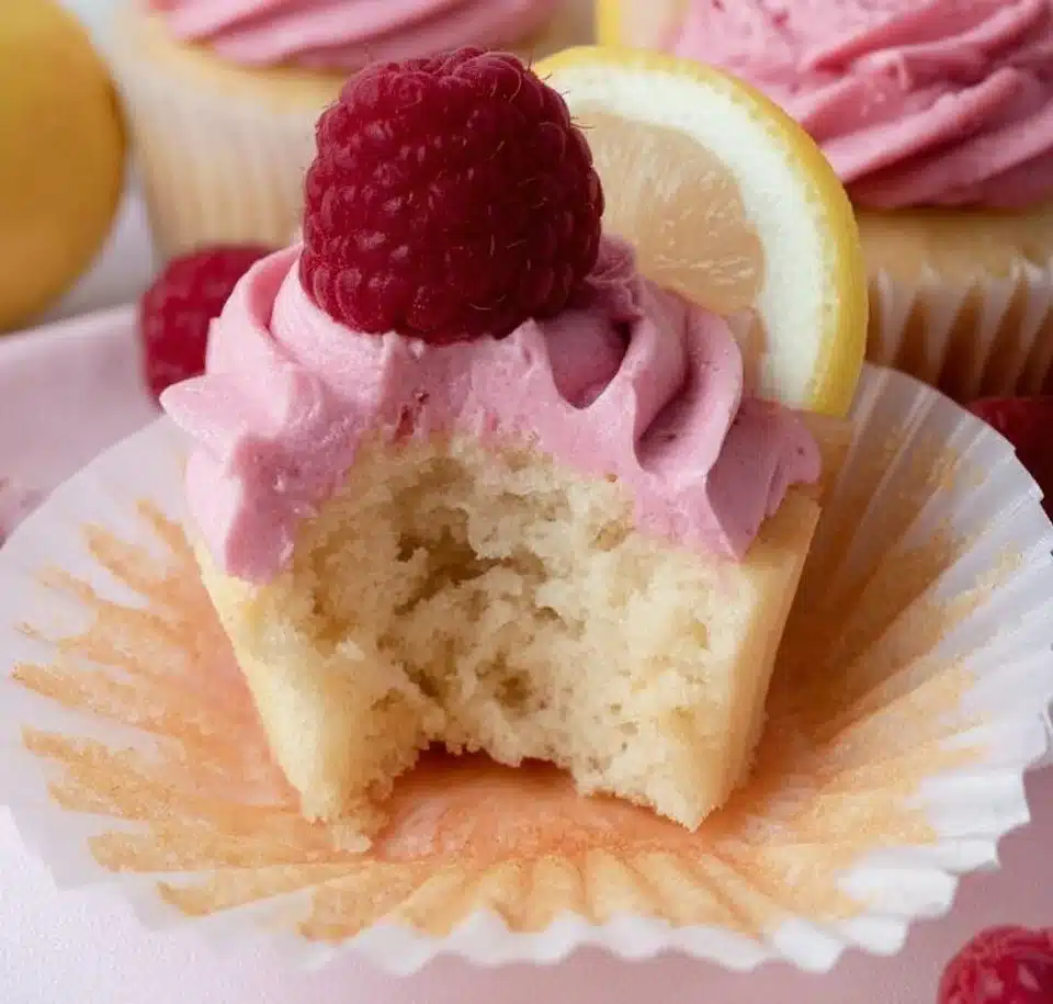 Lemon cupcakes with raspberry buttercream frosting on a plate.