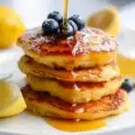 Plate of fluffy Lemon Ricotta Pancakes with lemon slices and syrup
