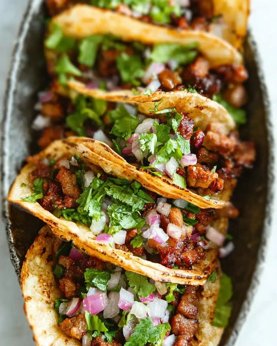 A plate of delicious Mexican street tacos topped with fresh cilantro and onions.