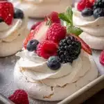 Mini pavlovas topped with fresh berries on a serving platter