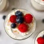 No-bake cheesecake cups served in a clear glass with berry toppings