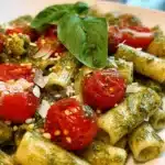 Pesto pasta topped with fresh cherry tomatoes for a vibrant dish
