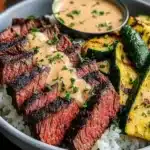 Delicious Steak Bowl topped with savory sauce and fresh zucchini.