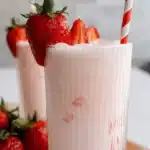 A glass of strawberry horchata garnished with fresh strawberries