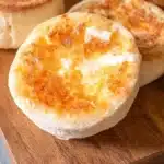 Freshly baked English muffins on a wooden cutting board