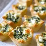 Delicious feta spinach tartlets served on a wooden platter.