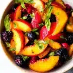 Delicious honey lime basil peach fruit salad in a bowl garnished with fresh basil