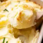 Creamy mashed potatoes served with gravy in a white bowl