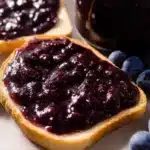 Homemade blueberry butter spread on toasted bread with fresh blueberries on the side.