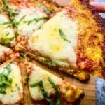 Cauliflower pizza crust topped with fresh ingredients and herbs