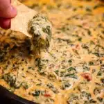 Creamy spinach queso dip served in a bowl with tortilla chips.