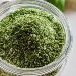 Basil salt in a small bowl with fresh basil leaves for seasoning.