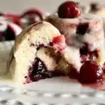 Freshly baked Cherry Cinnamon Rolls drizzled with icing on a plate.
