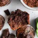 Baked chocolate zucchini muffins stacked on a plate, rich in flavor and moist texture.