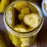A jar of homemade dill pickles with fresh dill and spices inside.
