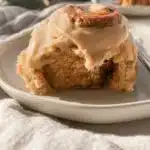 Delicious gingerbread cinnamon rolls topped with icing and festive spices.