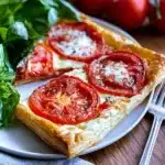 A delicious puff pastry tomato tart garnished with fresh herbs